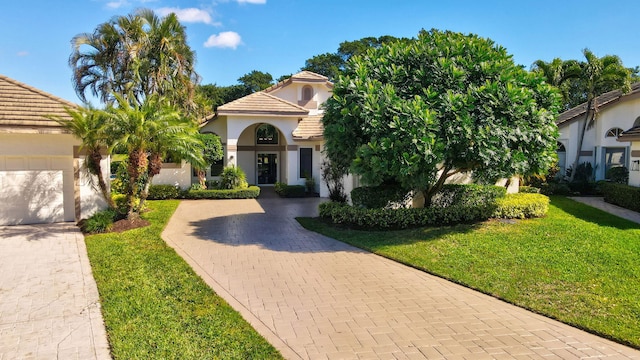 mediterranean / spanish-style house featuring a garage and a front yard