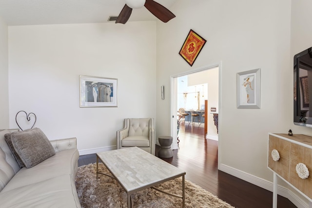 living room featuring ceiling fan, a towering ceiling, and dark hardwood / wood-style floors