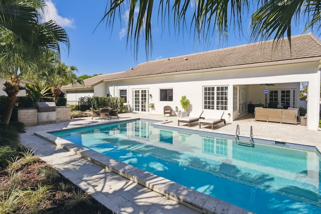 view of pool with french doors, an outdoor kitchen, ceiling fan, and a patio