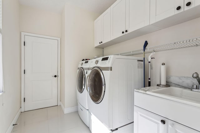 clothes washing area with cabinets, sink, light tile patterned floors, and washing machine and clothes dryer