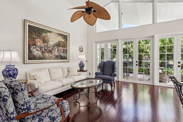 living room featuring dark hardwood / wood-style floors, french doors, ceiling fan, and a towering ceiling