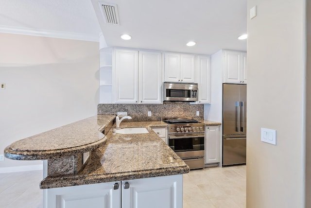 kitchen with high quality appliances, white cabinetry, sink, backsplash, and kitchen peninsula