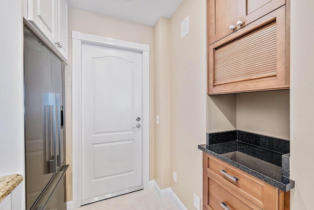 kitchen with light tile patterned flooring and dark stone counters