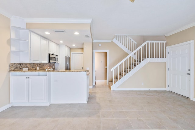 kitchen with light stone counters, ornamental molding, stainless steel appliances, and white cabinets