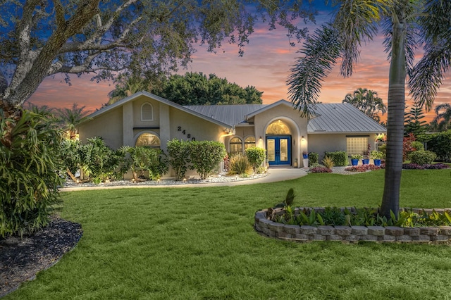 view of front of property with french doors and a lawn