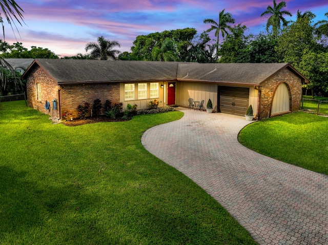 ranch-style home with a garage and a yard