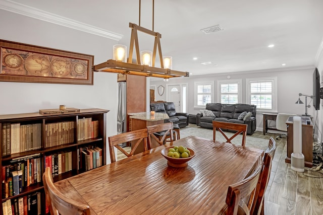 dining area featuring light wood-type flooring and ornamental molding