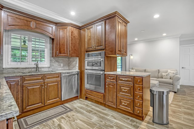 kitchen featuring appliances with stainless steel finishes, decorative backsplash, light stone countertops, ornamental molding, and sink