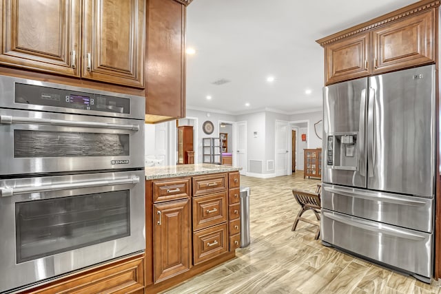 kitchen featuring light wood-type flooring, appliances with stainless steel finishes, crown molding, and light stone counters