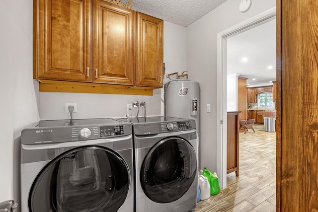 laundry room with cabinets, a textured ceiling, and washing machine and dryer