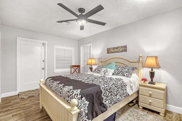 bedroom with a textured ceiling, ceiling fan, and hardwood / wood-style floors