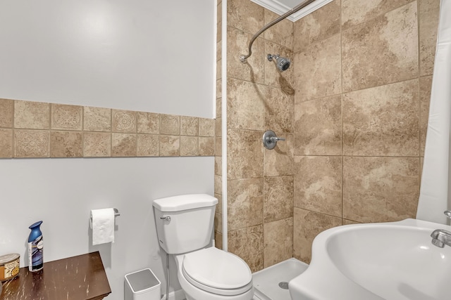 bathroom with toilet, sink, and tiled shower