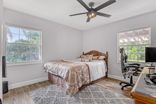 bedroom featuring a textured ceiling, ceiling fan, and light hardwood / wood-style floors