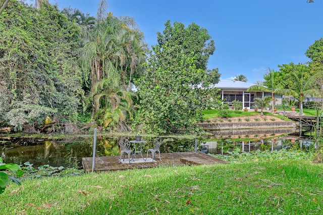 view of yard featuring a sunroom and a water view