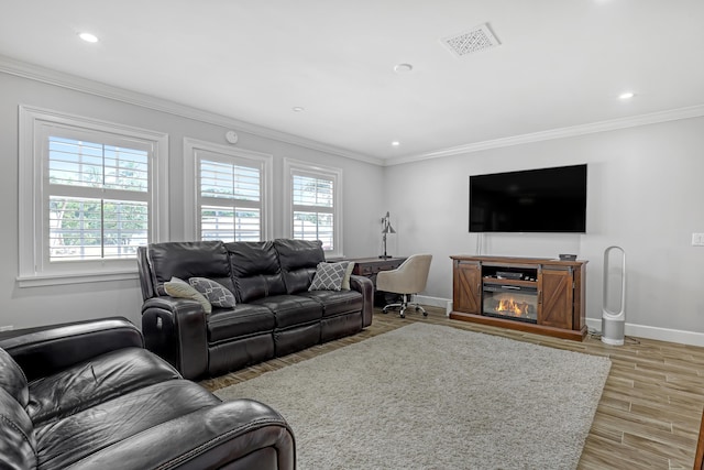 living room with wood-type flooring, ornamental molding, and a healthy amount of sunlight