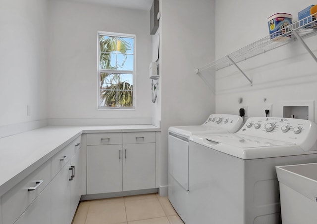 washroom with light tile patterned floors, washing machine and dryer, sink, and cabinets