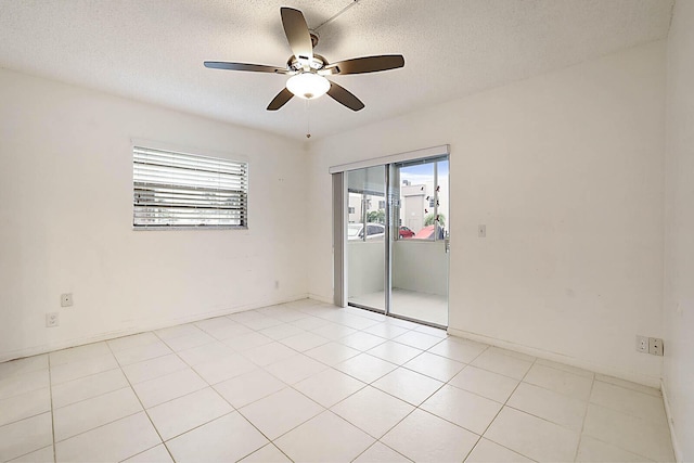 empty room with a textured ceiling, ceiling fan, and light tile patterned floors