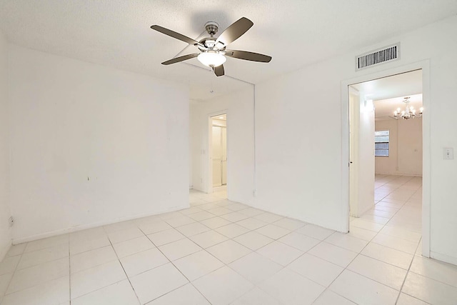 spare room with ceiling fan with notable chandelier and light tile patterned floors