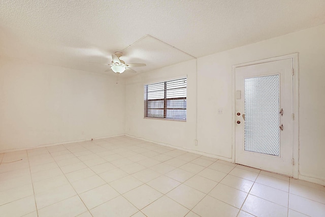 spare room with ceiling fan, a textured ceiling, and light tile patterned floors