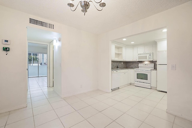 kitchen with a textured ceiling, backsplash, white cabinets, and white appliances