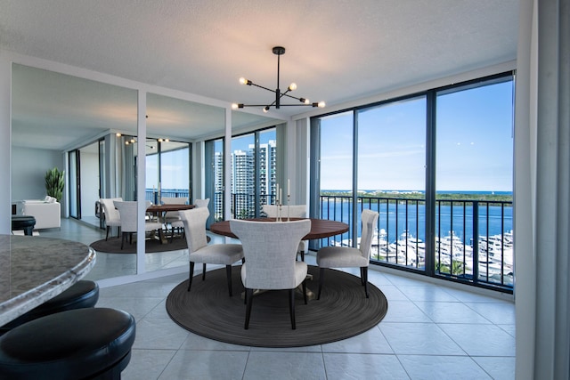 tiled dining space with expansive windows, a water view, an inviting chandelier, and a textured ceiling