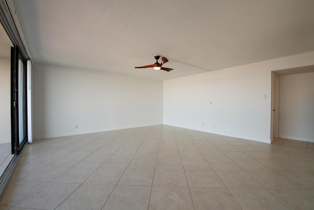 empty room with light tile patterned floors, baseboards, and ceiling fan