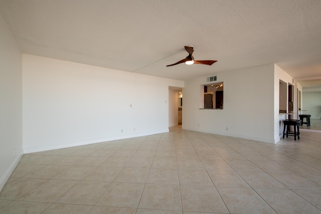 unfurnished room with a ceiling fan, baseboards, visible vents, light tile patterned flooring, and a textured ceiling