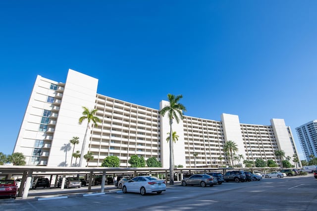 view of building exterior featuring covered and uncovered parking