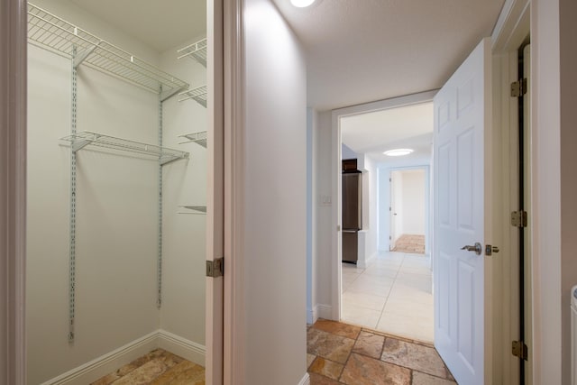 hall featuring baseboards and stone finish floor