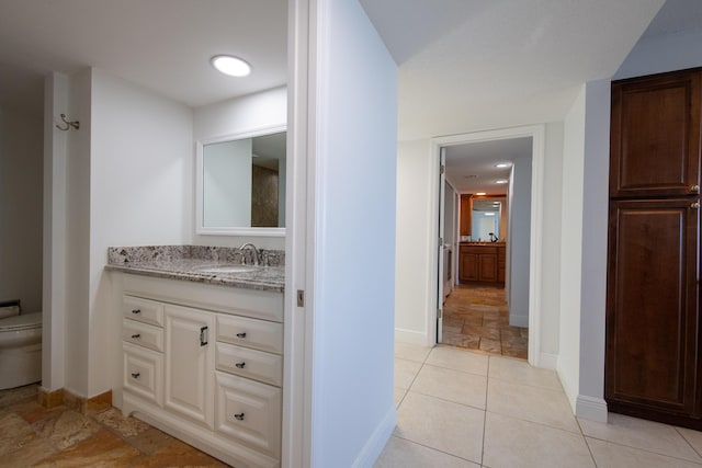 bathroom featuring toilet, vanity, and baseboards