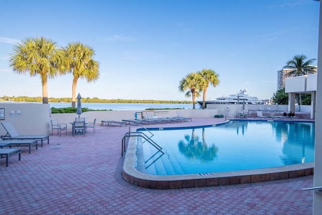 view of swimming pool with a patio area and a water view