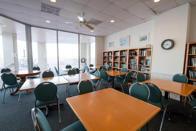 office area featuring a drop ceiling, ceiling fan, and expansive windows