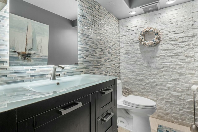 bathroom featuring vanity, tile walls, and toilet