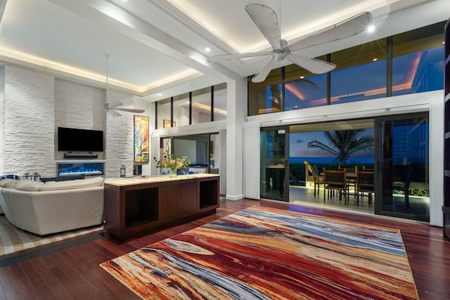 living room featuring dark hardwood / wood-style flooring, a raised ceiling, and ceiling fan