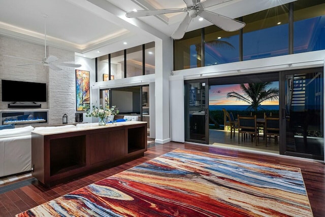 living room with dark hardwood / wood-style flooring, a towering ceiling, and ceiling fan