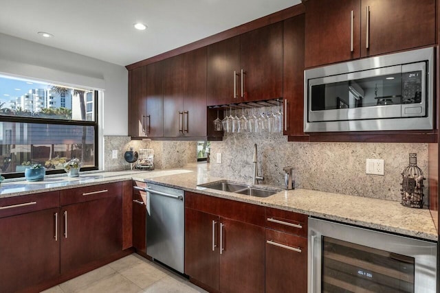 kitchen with wine cooler, sink, stainless steel appliances, light stone countertops, and decorative backsplash