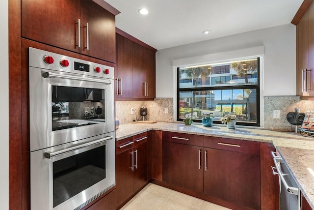 kitchen with light stone counters, stainless steel appliances, light tile patterned flooring, and backsplash