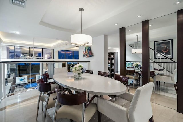 dining area with light tile patterned floors and a raised ceiling