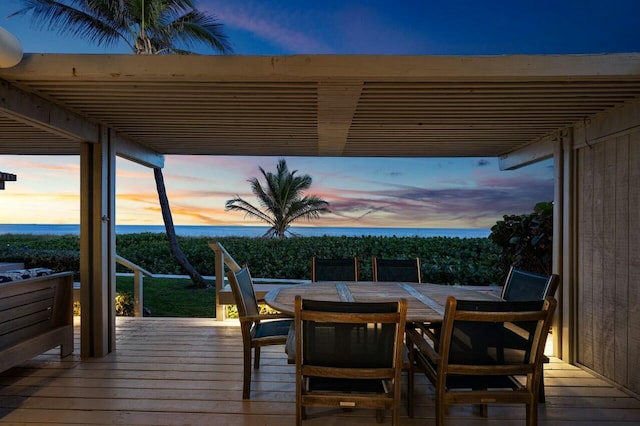 deck at dusk featuring a water view