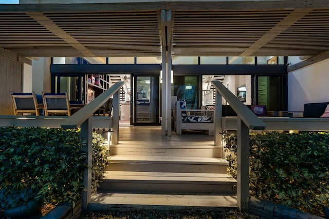 entrance to property featuring a wooden deck and a pergola