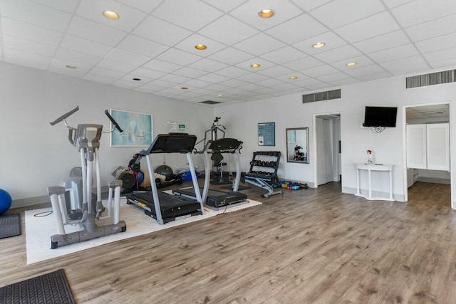 exercise room with wood-type flooring and a drop ceiling