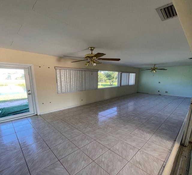 tiled empty room with ceiling fan and plenty of natural light