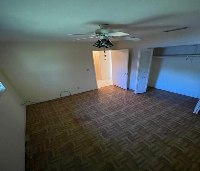 unfurnished bedroom featuring ceiling fan and dark parquet flooring