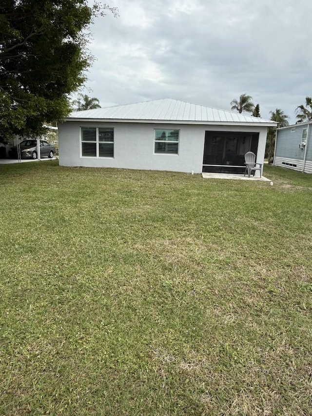 rear view of property featuring a yard and a sunroom