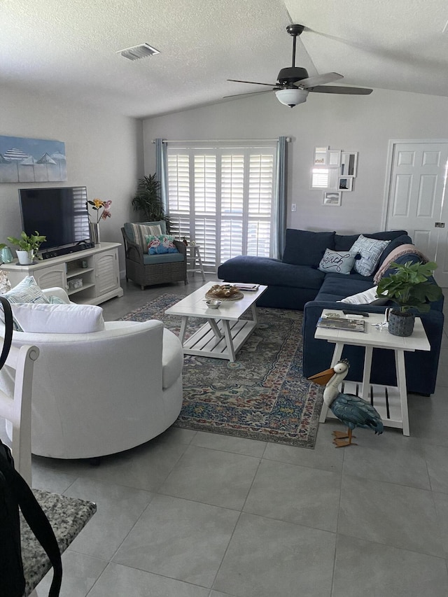 tiled living room featuring lofted ceiling, ceiling fan, and a textured ceiling