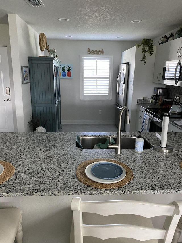 kitchen featuring white cabinetry, appliances with stainless steel finishes, and light stone counters