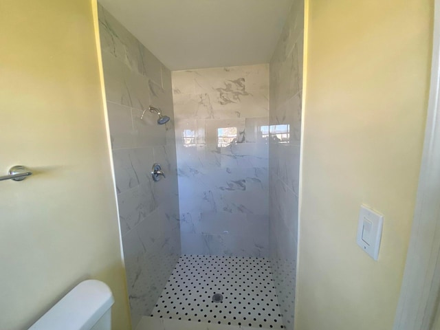 bathroom featuring tiled shower and toilet