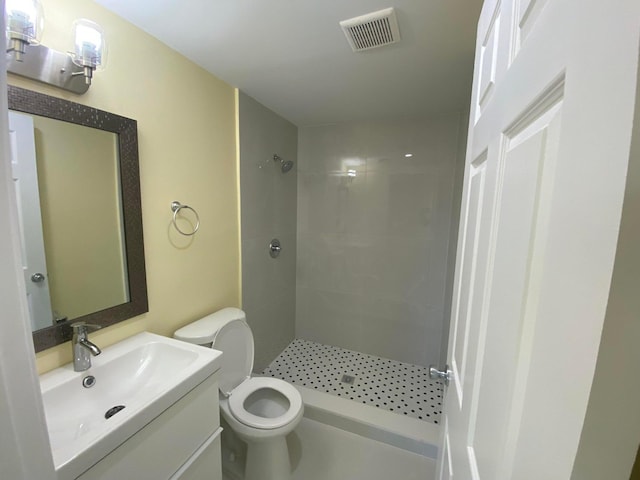 bathroom featuring toilet, tiled shower, and vanity