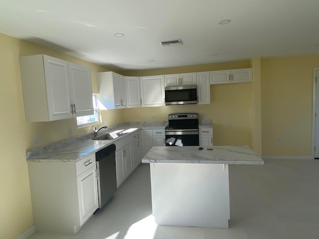 kitchen featuring appliances with stainless steel finishes, a center island, white cabinets, and sink