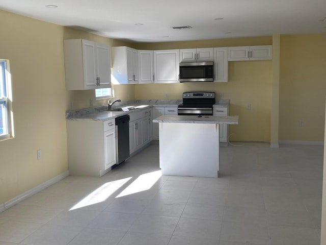 kitchen with stainless steel appliances, a center island, a wealth of natural light, white cabinets, and sink